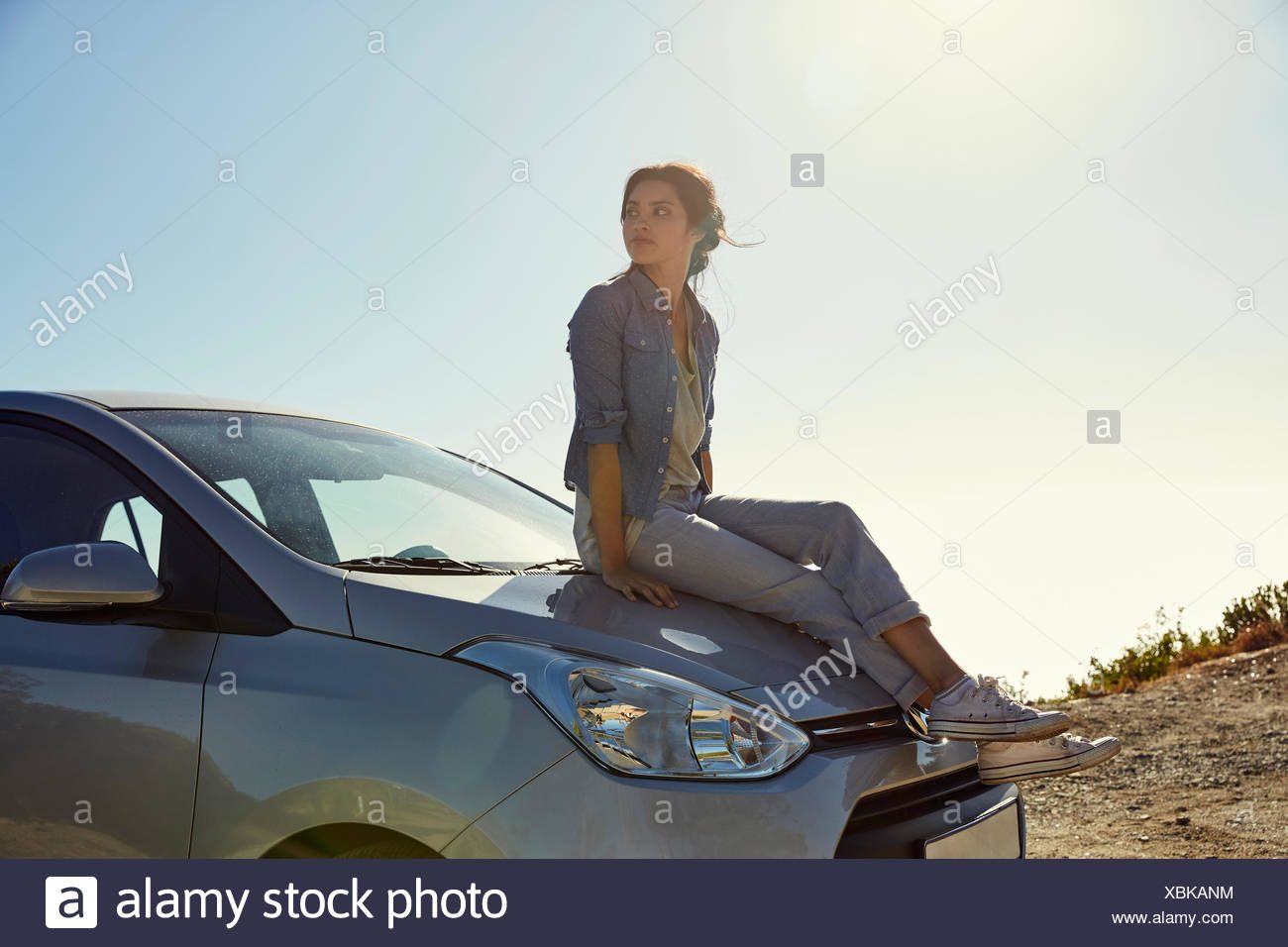 young-woman-sitting-on-a-car-looking-around-XBKANM.jpg