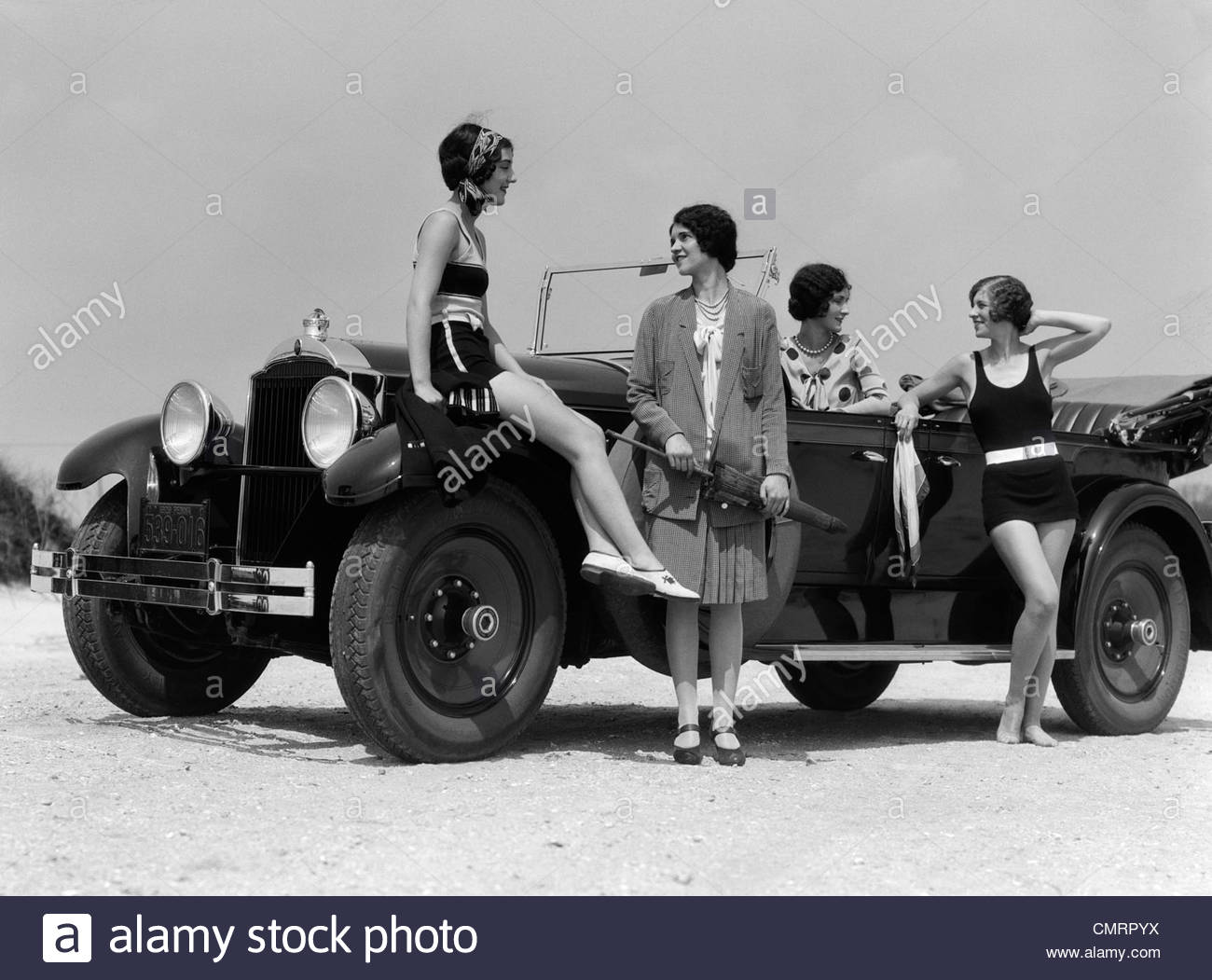 1920s-1930s-vier-frauen-auf-touring-cabrio-am-meeresufer-gekleidet-zwei-badeanzuge-zwei-fur-outdoor-mode-cmrpyx.jpg